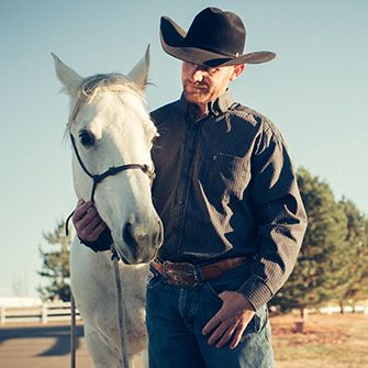 a man wearing a cowboy hat with a white horse