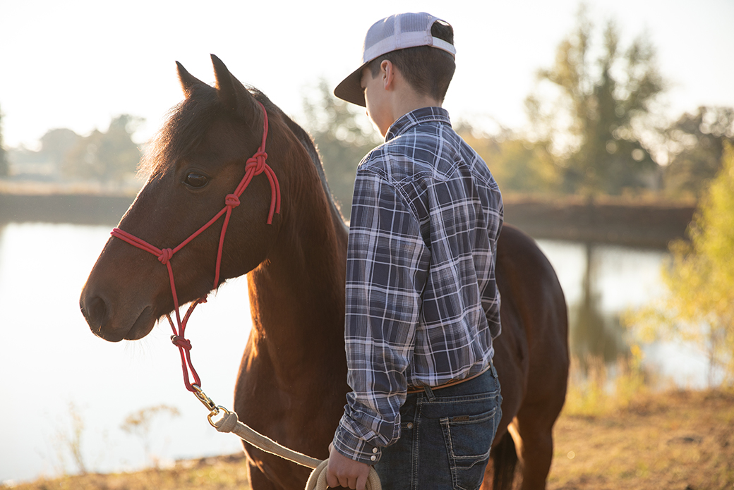 a boy in a flannel, blue jeans, and a white trucker hat next to Hero